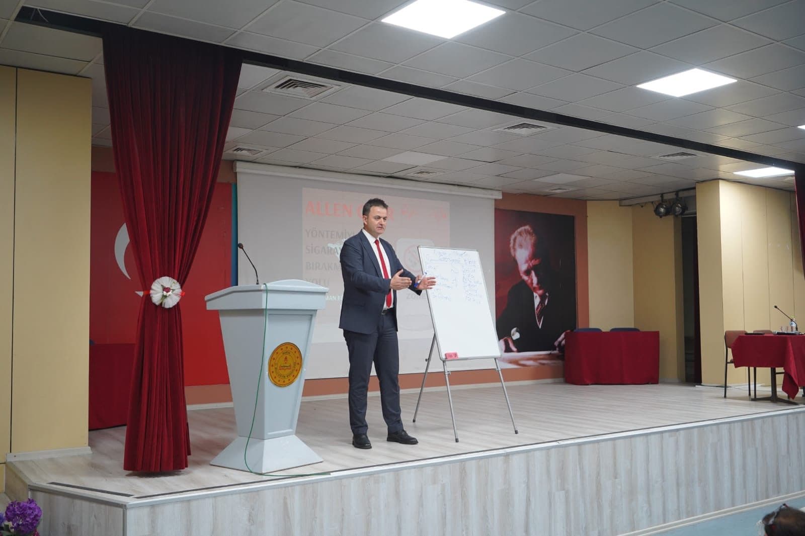 Aydoğan Tantürkü, Allen Carr yöntemi sunumu önünde ayakta seminer anlatırken