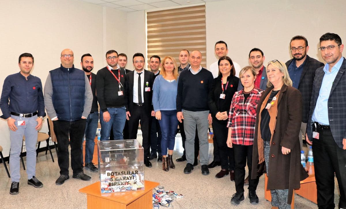 Kurumsal eğitim sonunda sigara paketlerini bırakma kutusunun çevresinde toplanan çalışanlar